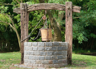 Outdoor well water system with wooden framing and brick stone base.